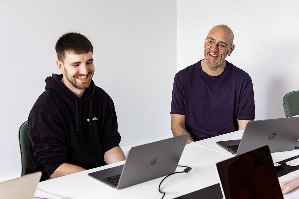 Two Schudio colleagues laughing at the office table